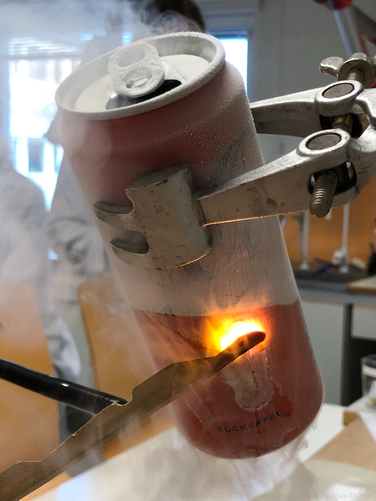 Flytande syre på aluminiumburkens utsida antänder en glödande trästicka.
